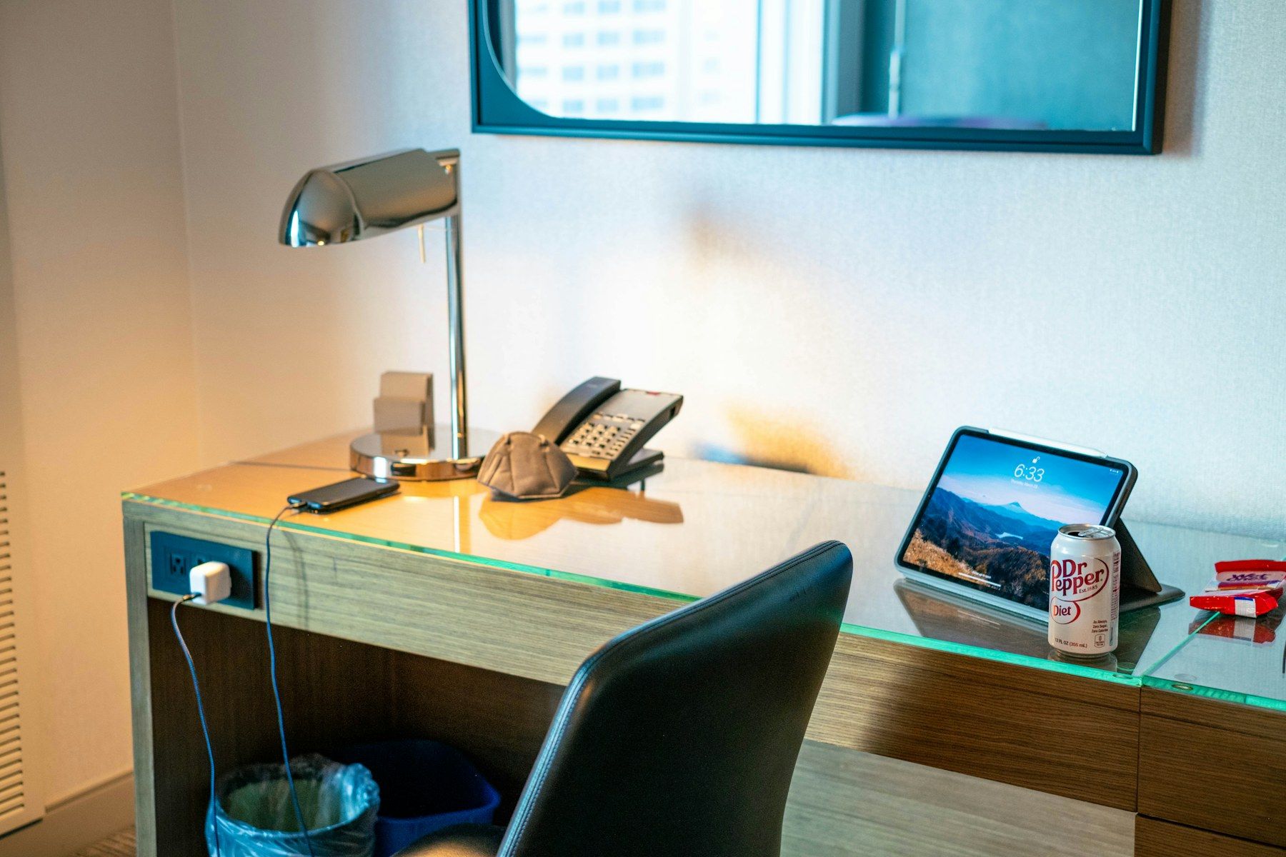 Tablet und Telefon auf dem Schreibtisch eines Hotelzimmers als Symbol für digitale Reservierungsdaten.